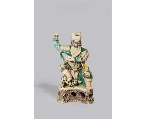 A CHINESE SANCAI FIGURE OF GUANDI KANGXI 1662-1722 Seated on a stool, wearing a suit of armour, holding an ingot in his left 