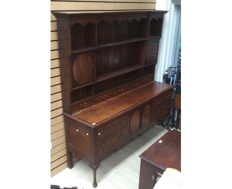 A George III oak dresser with rack, the base with four drawers and two doors between, the rack section with cupboard doors an
