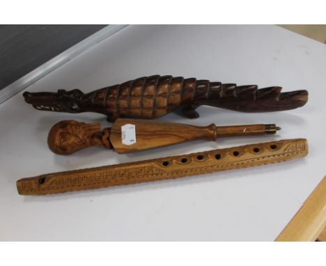 Three African style wooden items including a recorder, crocodile figure, and an item with a mans head on