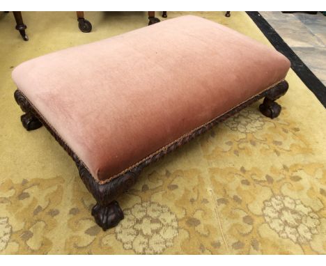 An early 20th Century mahogany pouffe raised on carved claw and ball feet