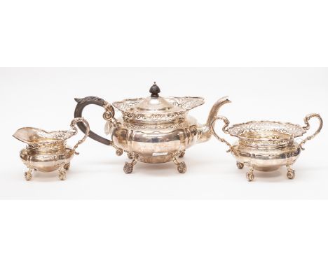 An Edwardian silver three piece tea service comprising teapot, sugar bowl and milk jug, reticulated flared apron above shaped
