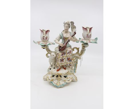 A Derby porcelain candelabrum, circa 1760-65, modelled as a shepherdess with lute and lamb, on Rococo scroll base, twin branc