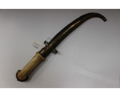 An Arabian Jambiya dagger with 21cm long curved double edged blade. Bone grip. Brass pommel. Complete with brass scabbard wit