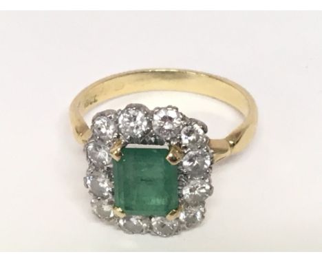 An 18carat gold ladies ring set with a a central rectangular emerald flanked by brilliant cut diamond of good colour possible