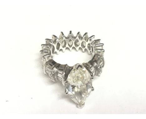 An exceptional platinum diamond ring the central Marquise cut diamond an impressive 6.20 carat approximately. Colour graded K