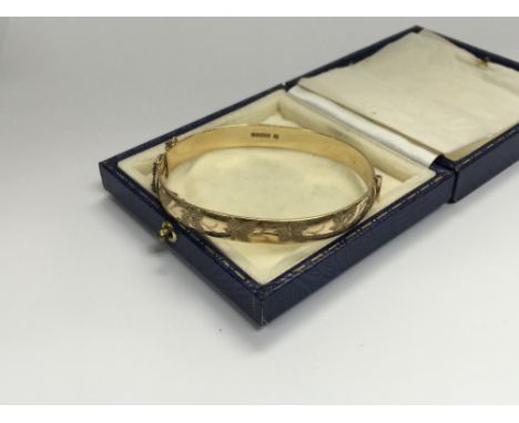 A 9ct gold bangle engraved with leaves and vines. Approx 23.5. Cat A