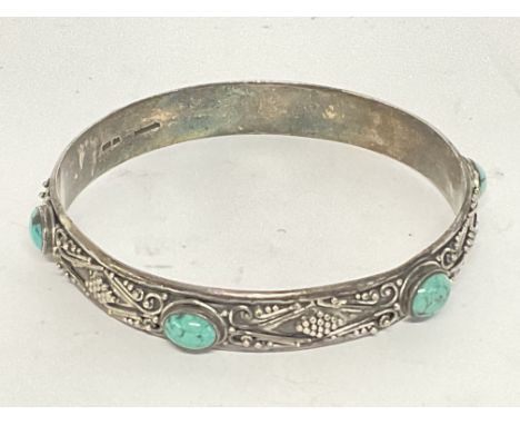 A heavy silver and turquoise bangle, postage cat A