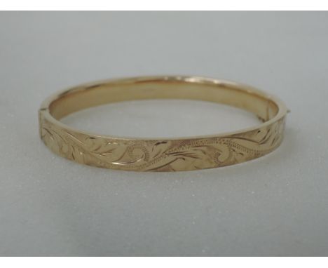 A 9ct gold hinged bangle having scroll engraving,  approx 11.5g