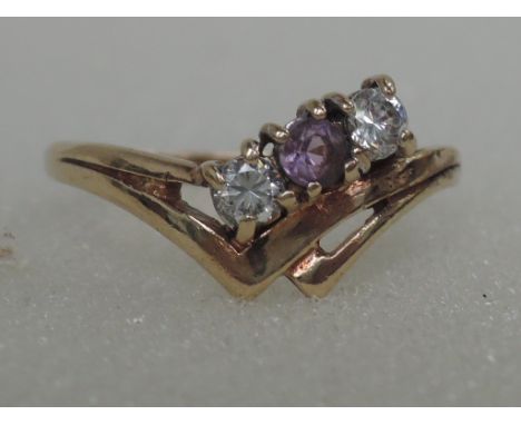 A ladies dress ring having a central amethyst flanked by two cubic zirconia in a double wishbone setting on a 9ct gold loop