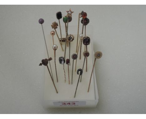 A collection of white and yellow metal stick pins of various designs including cultured pearl, amethyst, ruby, horse shoe etc