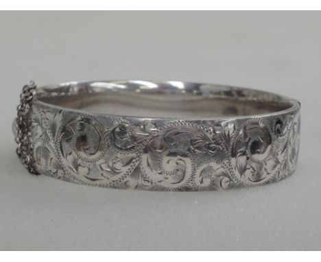 An HM silver hinged bangle having scroll decoration