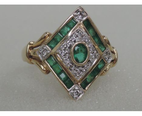 A ladies dress ring having emerald and diamond chips in an Art Deco style square setting on a yellow metal loop stamped 14K/5