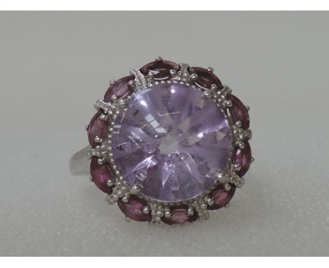 A ladies dress ring having a central amethyst cabouchon with amethyst illusion surround on a white metal loop stamped 925