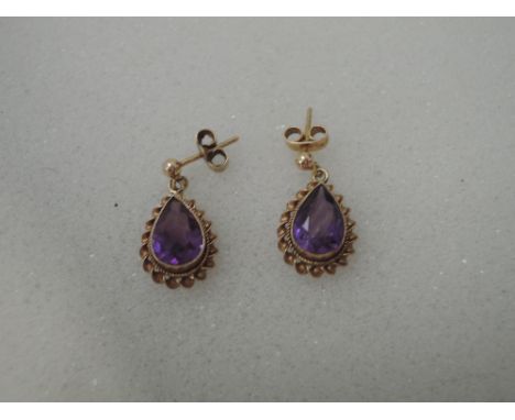 A pair of 9ct gold stud earrings having amethyst teardrops in a decorative gold mount