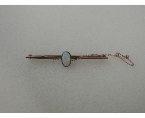 A yellow metal bar brooch stamped 9ct having a central oval opal