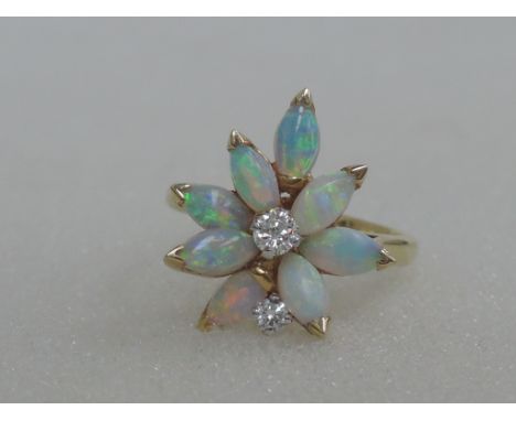 A ladies dress ring having a stylised opal and diamond daisy cluster in a raised basket mount on an 18ct gold loop