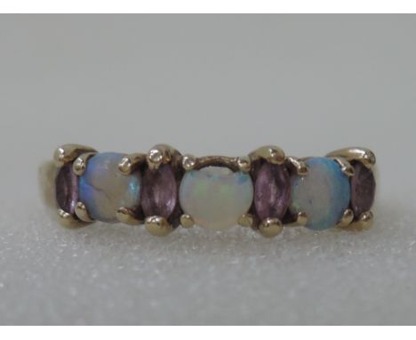 A ladies dress ring having three opals interspersed by pink sapphires on a 9ct gold loop, (1 opal AF)