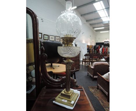 An Edwardian oil lamp having glass shade, with cut glass reservoir on brass Corinthian column stand