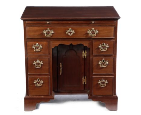 An early George III mahogany kneehole desk, with a brushing slide above an arrangement of seven drawers around a central cupb