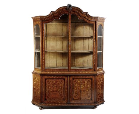 A Dutch kingwood and marquetry china display cabinet, of canted form, the arched pediment centred with a carved scrolling cre