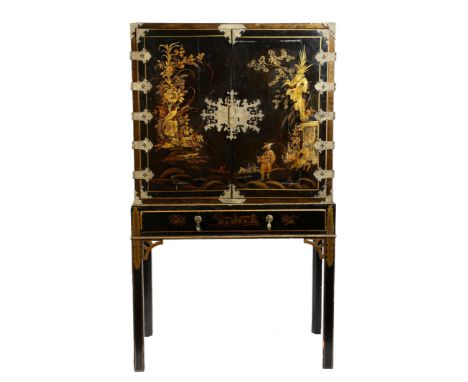 A black lacquered drinks cabinet on stand, decorated in gilt with chinoiserie, with a pair of doors, revealing an interior wi