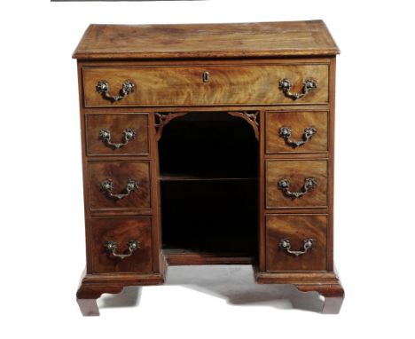 A George II mahogany kneehole desk, with an arrangement of seven drawers around an alcove with a shelf, with pierced brackets