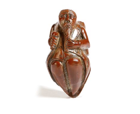 A French carved coquilla nut figural snuff box, in the form of a bearded soldier, holding a goblet, the hinged lid in the for