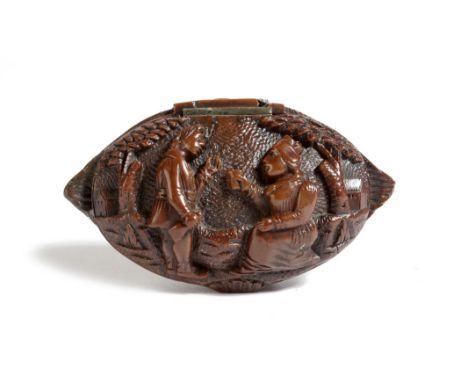 An early 19th century French carved coquilla nut snuff box, the hinged lid carved with a man and a woman drinking, with trees