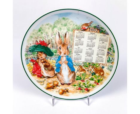 Collectors plate with an illustration of Peter Rabbit and Benjamin Bunny outside in the garden and calendar on surface with t