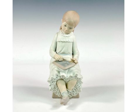 A child with her head tilted drawing on a chalkboard. NAO by Lladro backstamp. Issued: 1977Dimensions: 2"L x 2.5"W x 8"HManuf