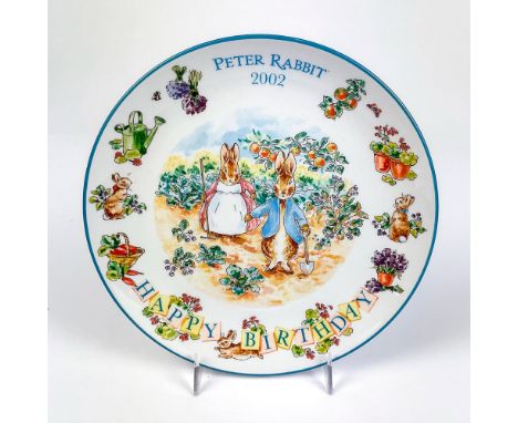 Collectors plate with an illustration of Peter Rabbit and Mrs. Rabbit in the garden with writing on surface and the year 2002