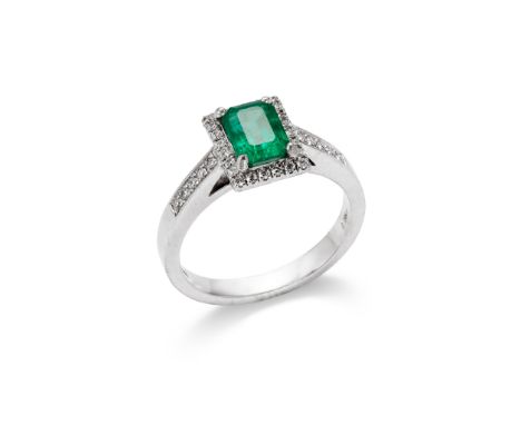 An emerald and diamond ring The cut-cornered rectangular-cut emerald to a brilliant-cut diamond surround and shoulders, mount