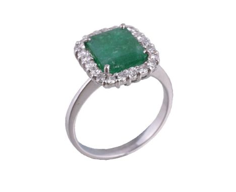 An emerald and diamond ring, the rectangular cut emerald claw set within a surround of brilliant cut diamonds, approximately 