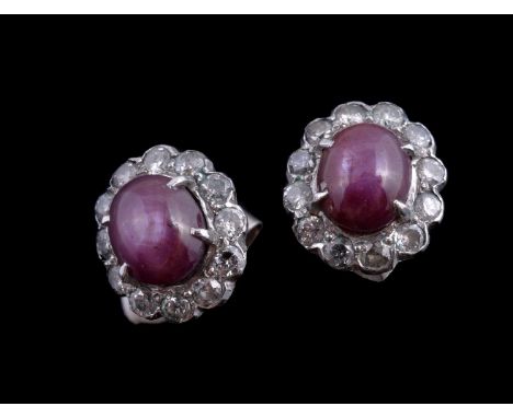 A pair of star ruby and diamond cluster earrings, the oval cabochon star ruby claw set within a surround of brilliant cut dia