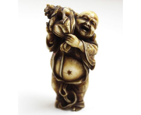 Carved Japanese Netsuke of a Buddha carrying a sack and a devil over his shoulder. Signed to reverse