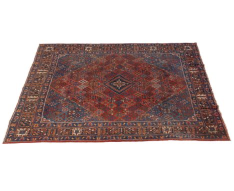 With a repeating diamond-shaped floral motif across a red ground with central medallions, and blue off-cut corners and a guar