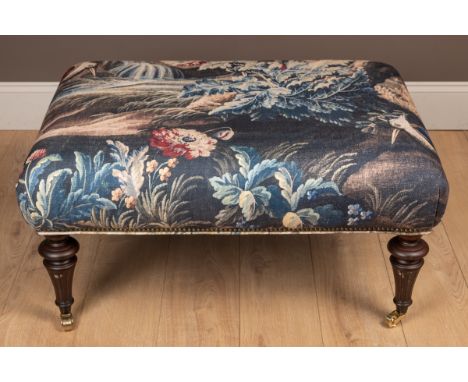 The top upholstered in a verdure tapestry style patterned material, standing on fluted tapering legs and terminating in brass