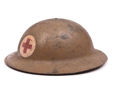 A WWI US Red Cross Brodie”s pattern steel helmet, painted red cross on white in roundel, leather chinstrap, oilcloth, netting