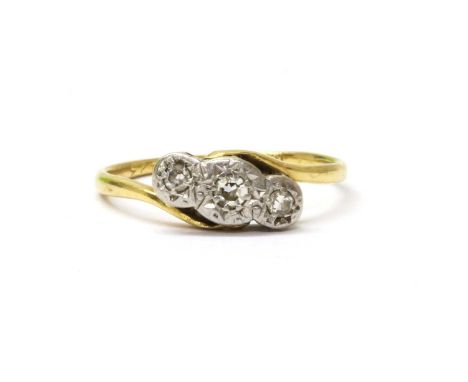 A gold three stone diamond crossover ring, with a row of graduated eight cut diamonds grain set to illusion collets, with cro