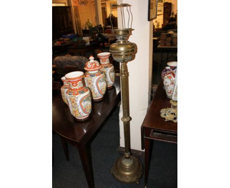 A Victorian brass oil lamp converted for use as a standard lamp, with reeded stem on circular base and ball feet, 149cm high