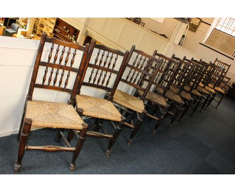 Ten rush seated ladder back dining chairs including one carver, each with two rows of turned spindles, the carver with three 