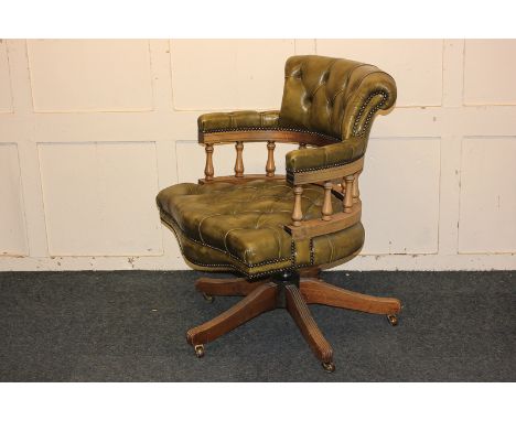A green leather button upholstered office chair with spindle back, on four splayed legs and castors