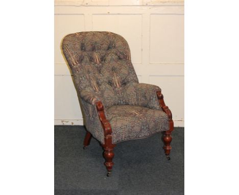 A Victorian button back armchair upholstered in William Morris style fabric, on turned baluster front legs and castors