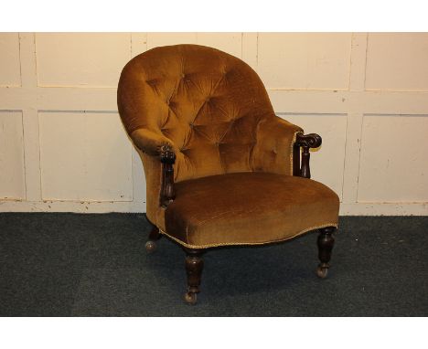 A Victorian button back armchair with gold upholstery and scrolled arms, on turned front legs (later castors)