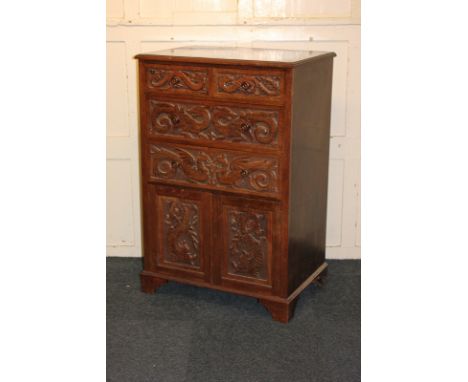 A carved chest of two short over two long drawers above a cupboard with twin panel doors enclosing a single shelf, the whole 