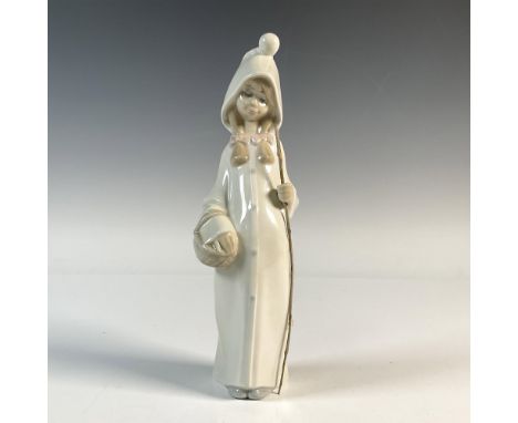 A glossy figure of a girl wearing a white cloak and pink bows, holding a basket and wooden stick. Lladro backstamp. This item