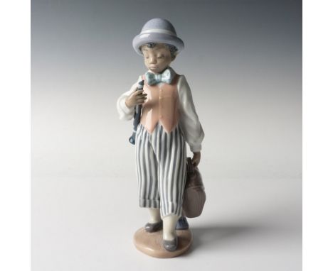 A glossy figure of a boy wearing striped pants and a polka-dot bow tie, holding a handbag and clarinet. Lladro backstamp. Art