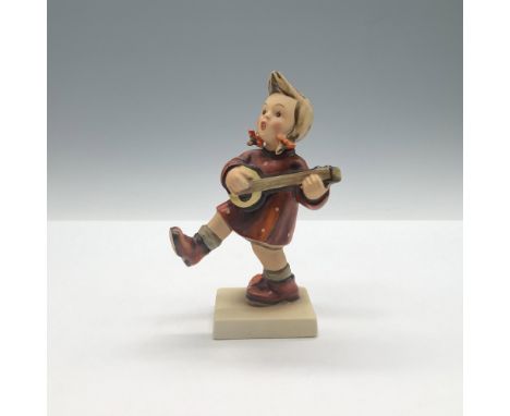 A matte hand painted figure of a young girl in a red polka dot dress walking while she in playing the guitar. Goebel backstam