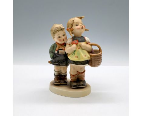 A matte hand painted porcelain figure of a girl holding a basket and orange flowers while standing next to a little boy who i