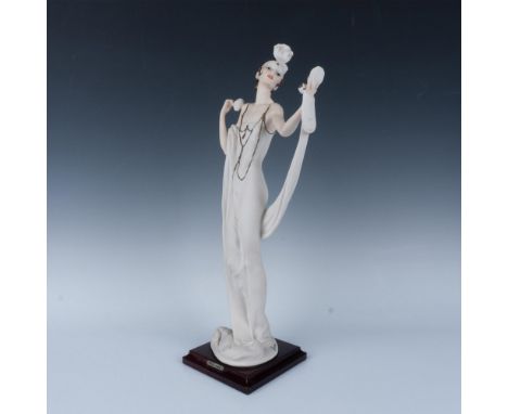 Art Deco figurine of a lady holding a powder puff and looking into a compact. The figurine is mounted on a square wooden base